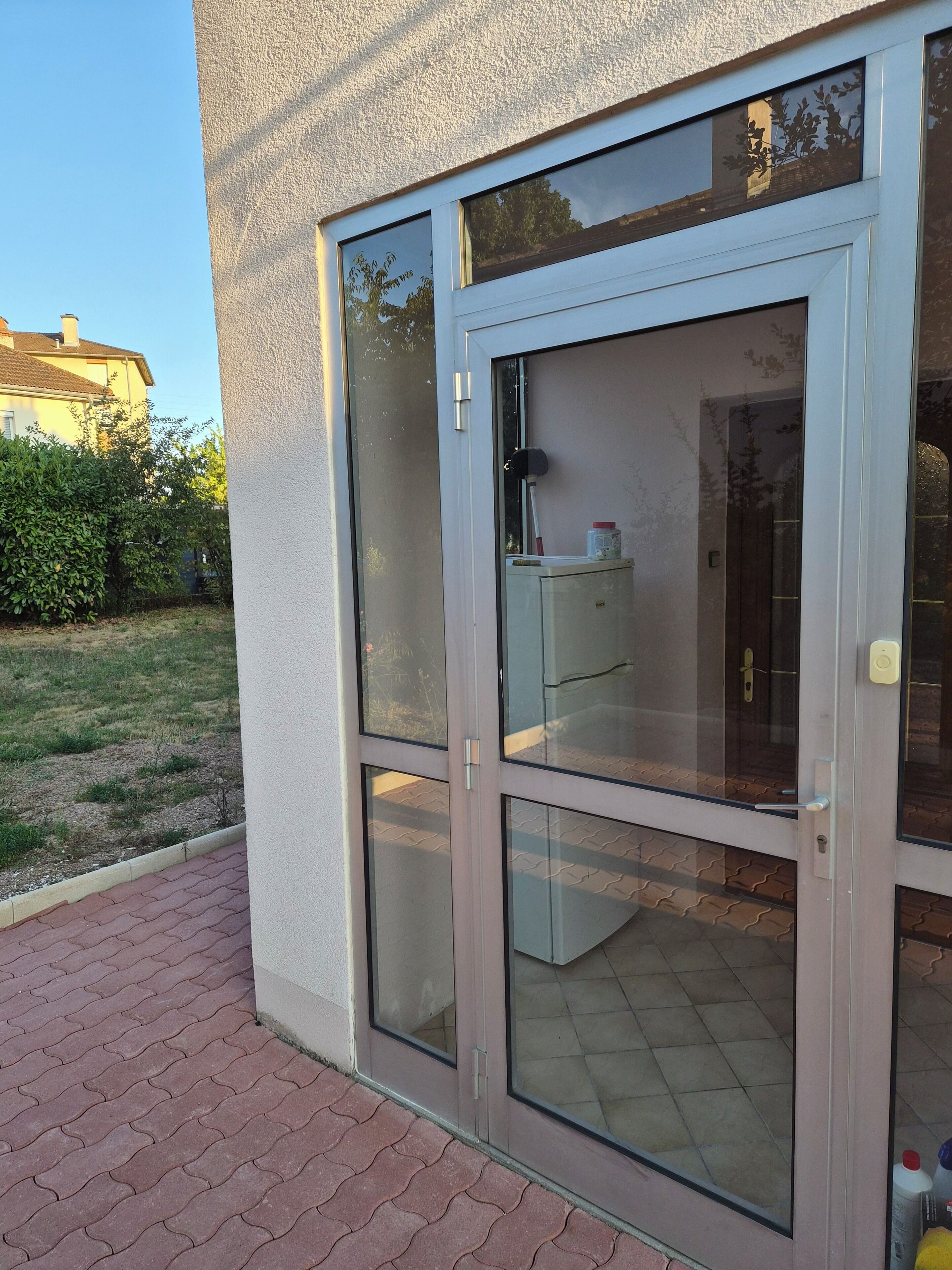 A building with a glass door and a small outdoor area with a paved walkway.