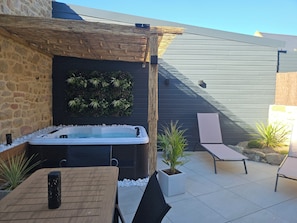 A hot tub, lounge chairs, and a stone wall with greenery. - Air-conditioned house for 4 people near the beach with a private heated spa (Erdeven)