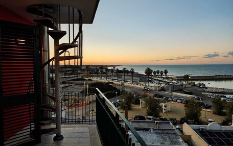 A balcony with a view of a coastal area, including a beach and a promenade.