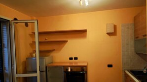 Una cocina compacta con refrigerador, horno y una pequeña mesa de comedor.