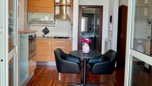 Cocina compacta con electrodomésticos modernos, una mesa de comedor con sillas y vista al baño contiguo.