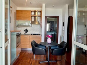Cocina compacta con electrodomésticos modernos, una mesa de comedor con sillas y vista al baño contiguo.