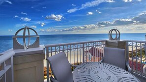 Ein Balkon mit Blick auf den Ozean, ausgestattet mit einem runden Tisch und zwei Stühlen.