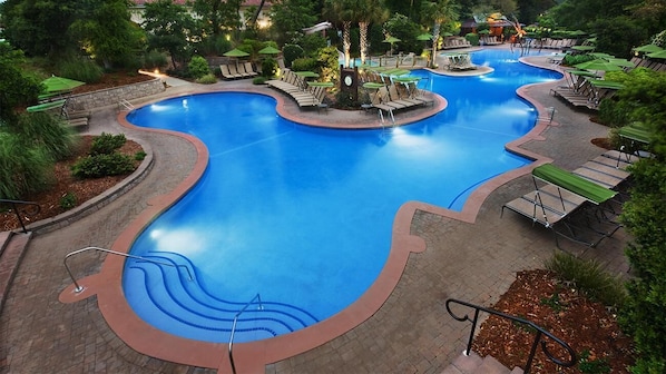 Ein großer, gewölbter Pool mit Liegestühlen und Sonnenschirmen.
