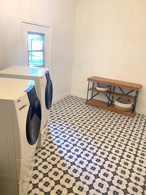 Ein Waschraum mit zwei Waschmaschinen, einem Holzregal mit Körben und einem Musterfußboden.