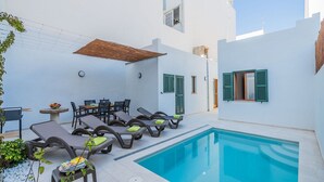 A poolside area with lounge chairs and a table, surrounded by white walls and a clear blue pool. - Central House With Pool, Puerto Pollenca (Pollença)