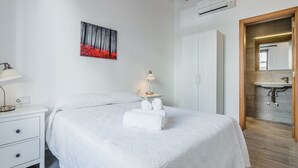 A hotel room with a bed, bedside tables, a painting, a wardrobe, and a bathroom with a sink and mirror. - Central House With Pool, Puerto Pollenca (Pollença)