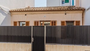 A building with a tiled roof, a numbered door, and a metal gate. - Central House With Pool, Puerto Pollenca (Pollença)