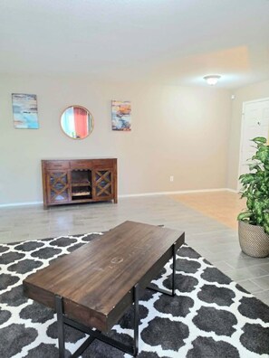 A spacious room with a wooden table, a patterned rug, a cabinet, and a potted plant. - Fully Loaded 4BR Cul-de-Sac Home with 3 Living Rooms, Game Room, & big backyard (Fort Worth)