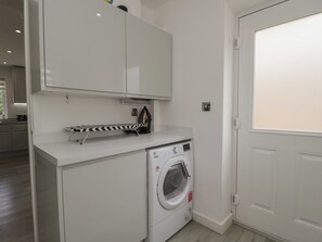 Una sala de lavandería con lavadora, tendedero y una puerta blanca.