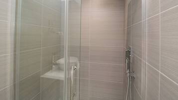 A glass-enclosed shower stall with a handheld showerhead and a wall-mounted rain showerhead.