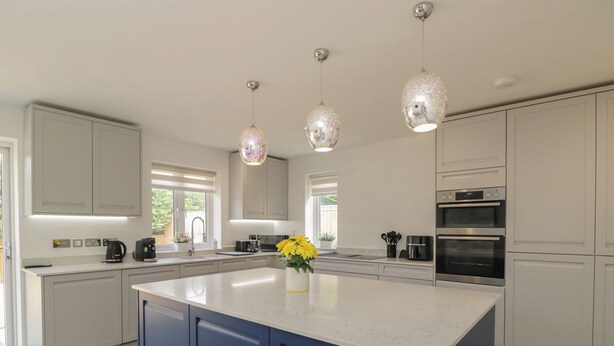 Una cocina moderna con una isla central, hornos dobles e iluminación colgante.