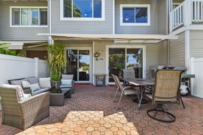 Eine überdachte Terrasse mit sechseckigen Fliesen, Gartenmöbeln und Blick auf das Haus.