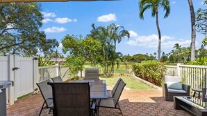 An outdoor patio with a table and chairs, surrounded by a white fence, palm trees, and a clear sky. - Wake Up to Golf Course Views & Resort Amenities (Kapolei)