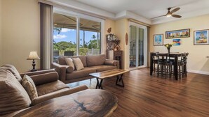 A spacious living area with a sofa, coffee table, and dining table. - Wake Up to Golf Course Views & Resort Amenities (Kapolei)