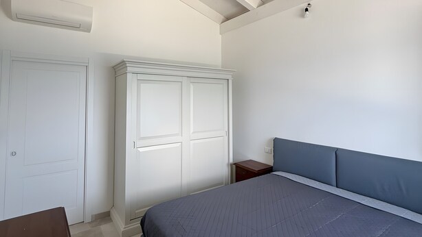 Ein Schlafzimmer mit Bett, Kleiderschrank und Deckenbalken.
