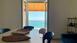 Ein Essbereich mit Blick auf das Meer, ein Tisch mit Unterlage und ein blauer Stuhl.
