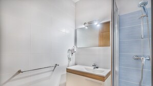Un baño moderno con ducha, lavamanos y espejo.