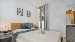 Habitación de hotel con cama, mesita de noche, lámpara, cómoda y ventana con cortinas.
