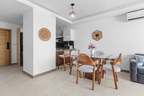 Ein modernes Wohnzimmer mit Essbereich, Küche und einem grauen Sofa.
