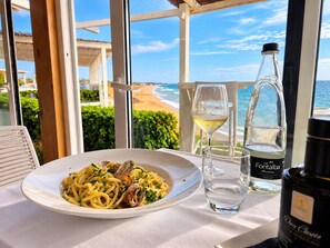 A table with a plate of pasta, a glass of white wine, and a bottle of water, overlooking a beach. - "Villa Anna tra le Dune" - Private parking. 
5 minutes by bike from the beach. (Santa Maria del Focallo)