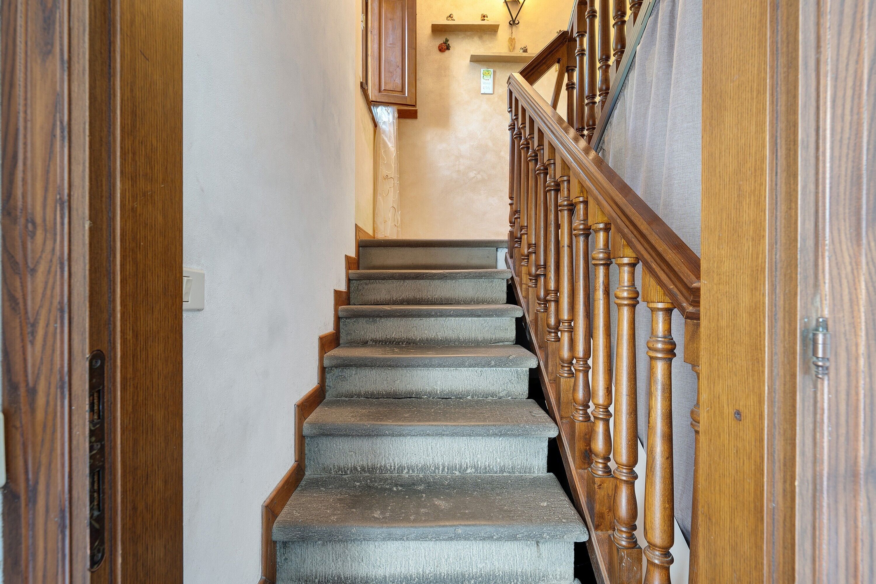 Un escalier avec des balustrades en bois et des marches recouvertes de moquette, menant à un palier.