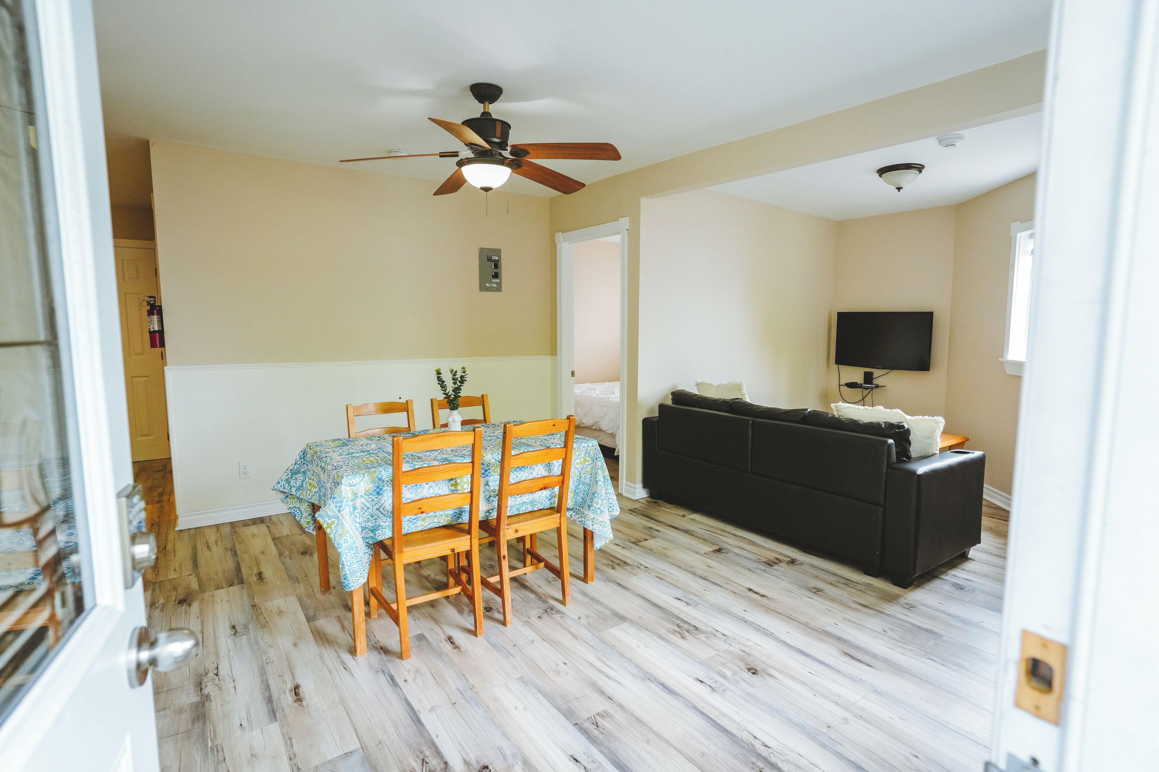 Une pièce comprenant une table à manger, des chaises, un ventilateur de plafond, un canapé et un téléviseur.