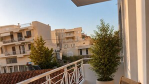 Un balcon avec une table préparée pour le petit-déjeuner, comprenant des toasts, des fruits et du jus d’orange.