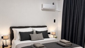 Une chambre moderne avec un grand lit, des lampes de chevet, un climatiseur fixé au mur et un rideau foncé.