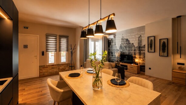 Une cuisine moderne dotée d’un îlot central, de planchers en bois et de luminaires suspendus.