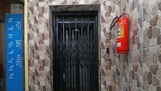 A stone wall with a metal gate and a fire extinguisher mounted on it. - Townhouse Hatia Railway Station (Ranchi)