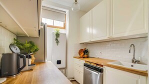 Une cuisine moderne avec des meubles blancs, un plan de travail en bois, un lave-vaisselle encastré et une machine à café.