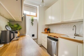 Eine moderne Küche mit weißen Schränken, einer Holzauskastung, einem eingebauten Geschirrspüler und einer Kaffeemaschine.