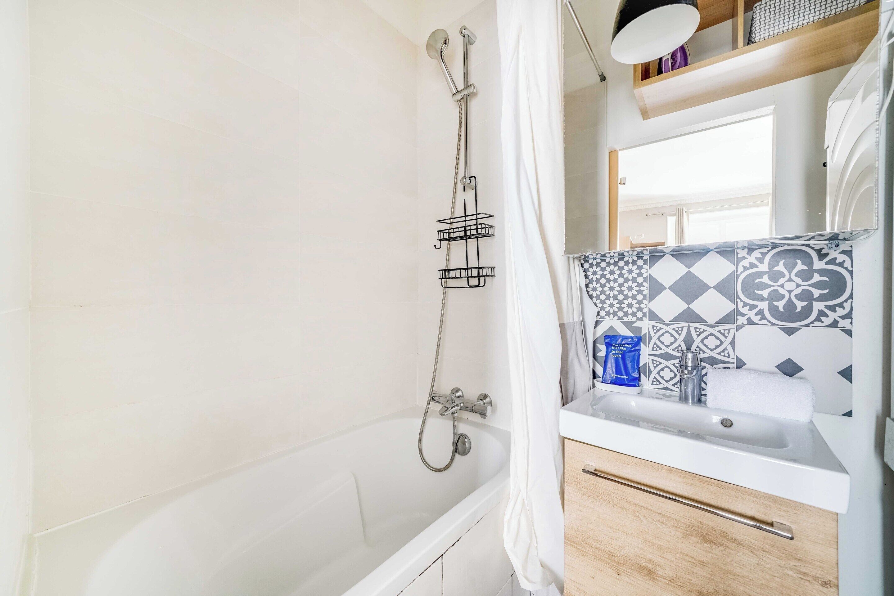 A bathroom with a bathtub, a shower, a sink, and a mirror.
