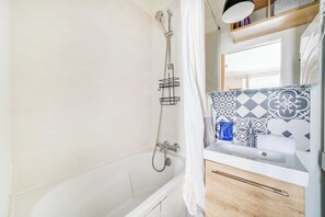 A bathroom with a bathtub, a shower, a sink, and a mirror. - Cozy Apartment 2br/3p - Paris 17e (Paris)