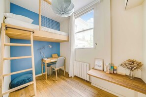 Ein Zimmer mit einem Etagenbett, einem Schreibtisch, einem Stuhl, einem Heizkörper und einem Fenster mit Blick.