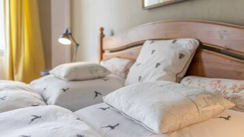 A neatly made bed with patterned bedding and pillows, a bedside lamp, and a framed picture on the wall.