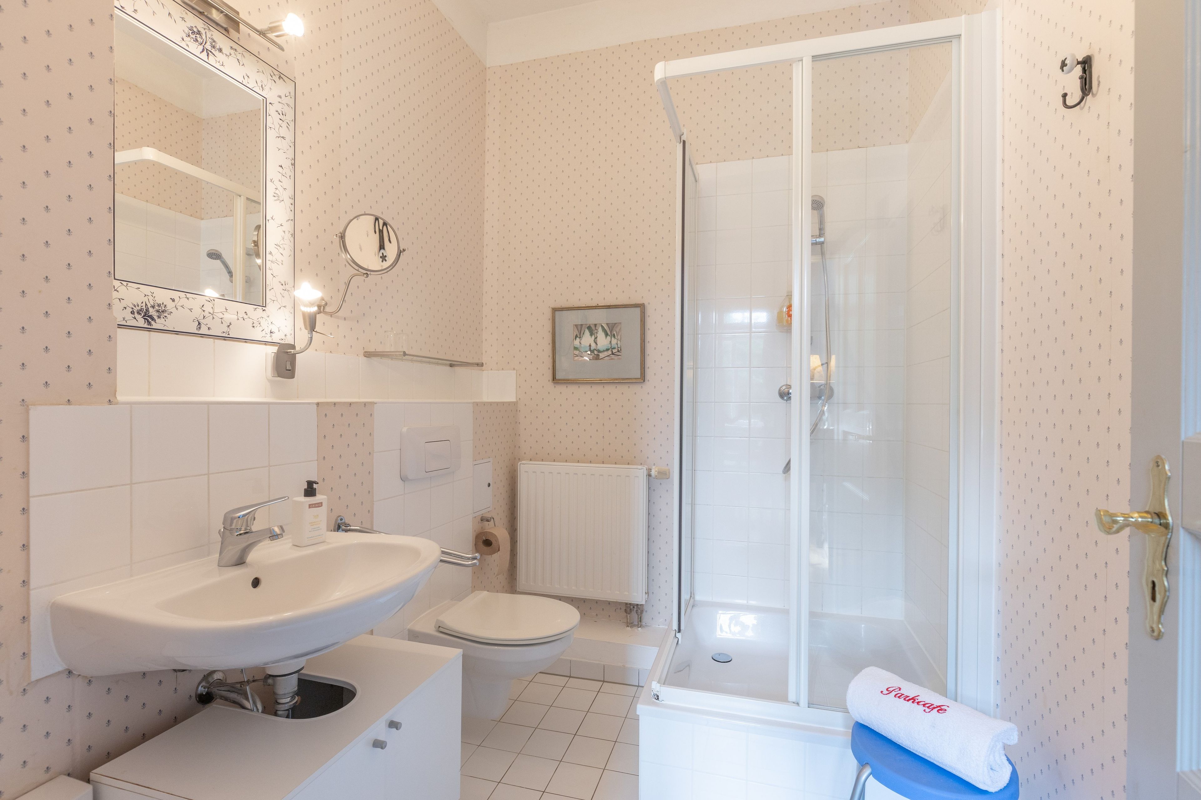 Ein Badezimmer mit Waschbecken, Toilette, Dusche und einem Handtuch auf einem Stuhl.