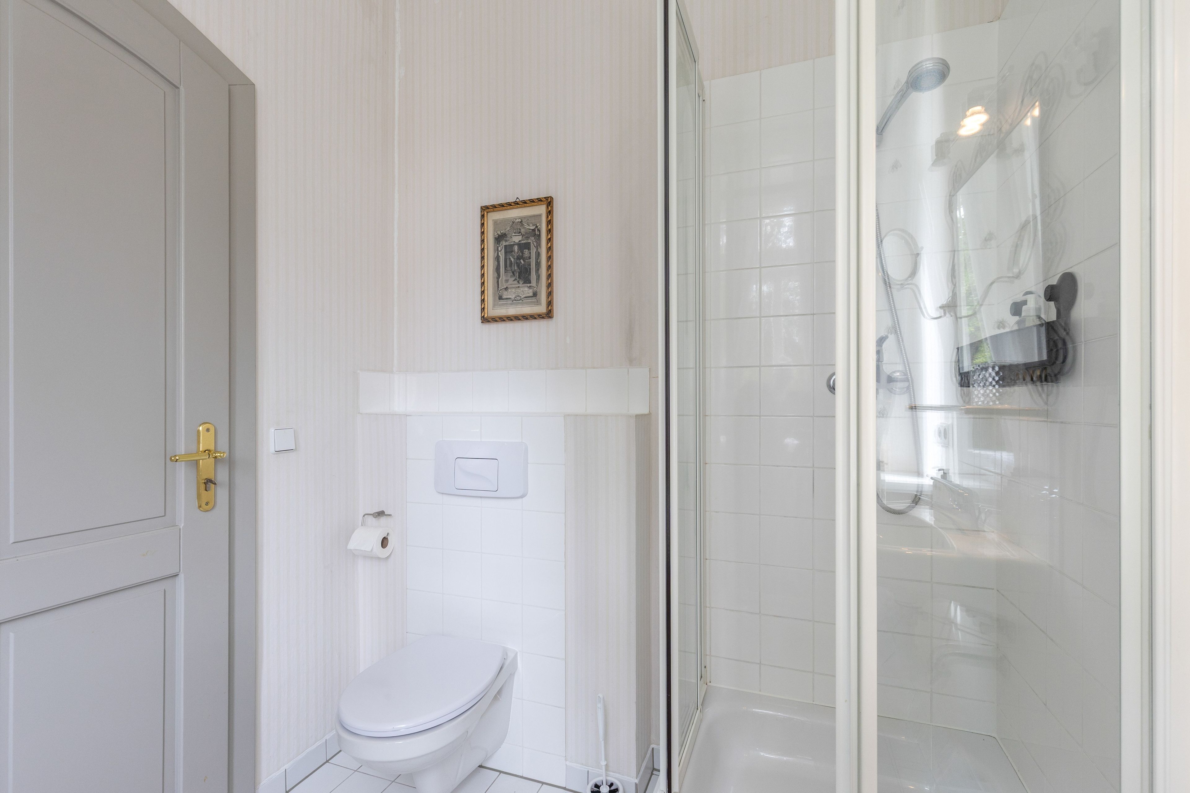 Ein Badezimmer mit Toilette, einer Duschkabine und einem gerahmten Bild an der Wand.