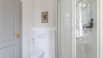 Ein Badezimmer mit Toilette, einer Duschkabine und einem gerahmten Bild an der Wand.
