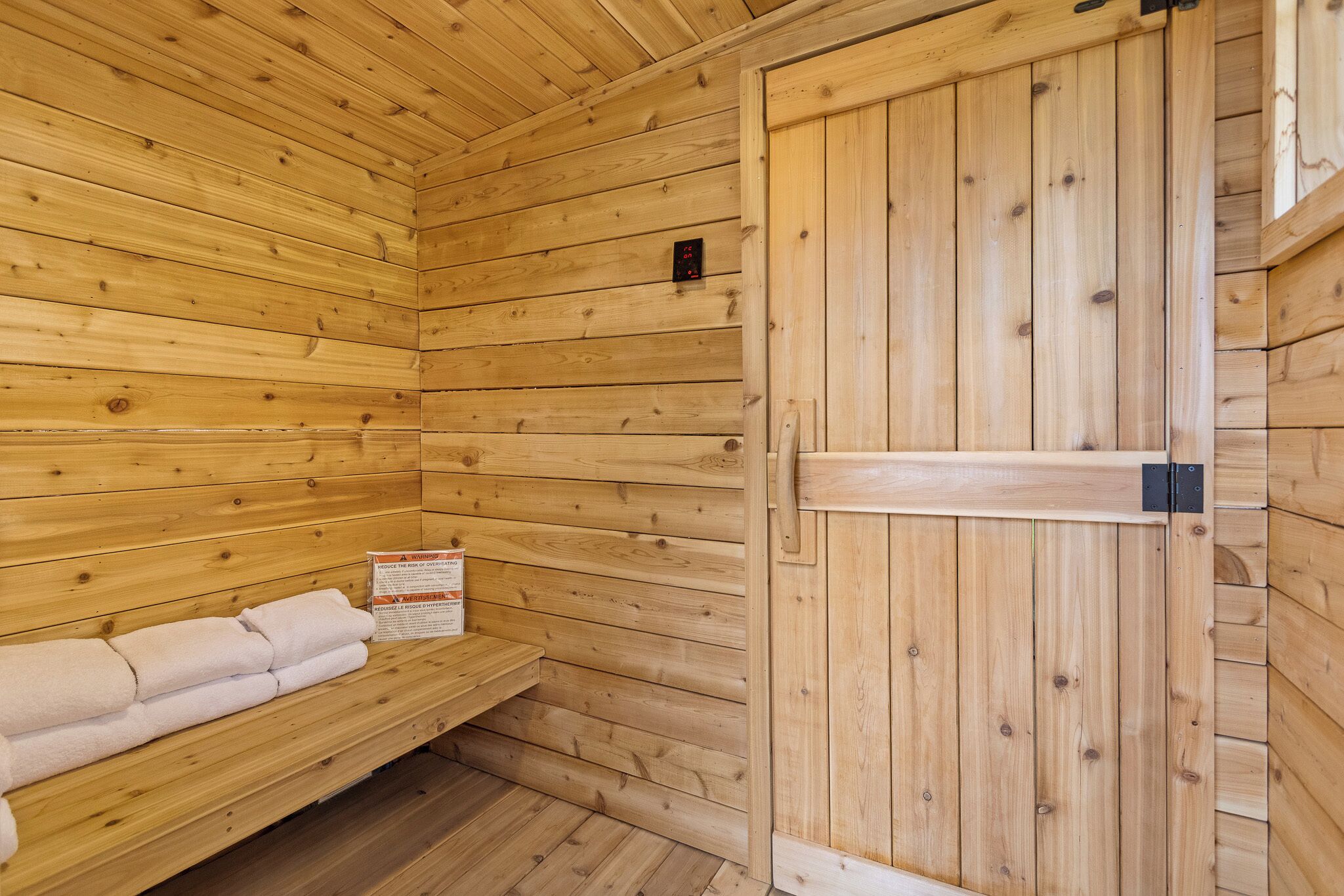 Un sauna de madera con un banco y una puerta.