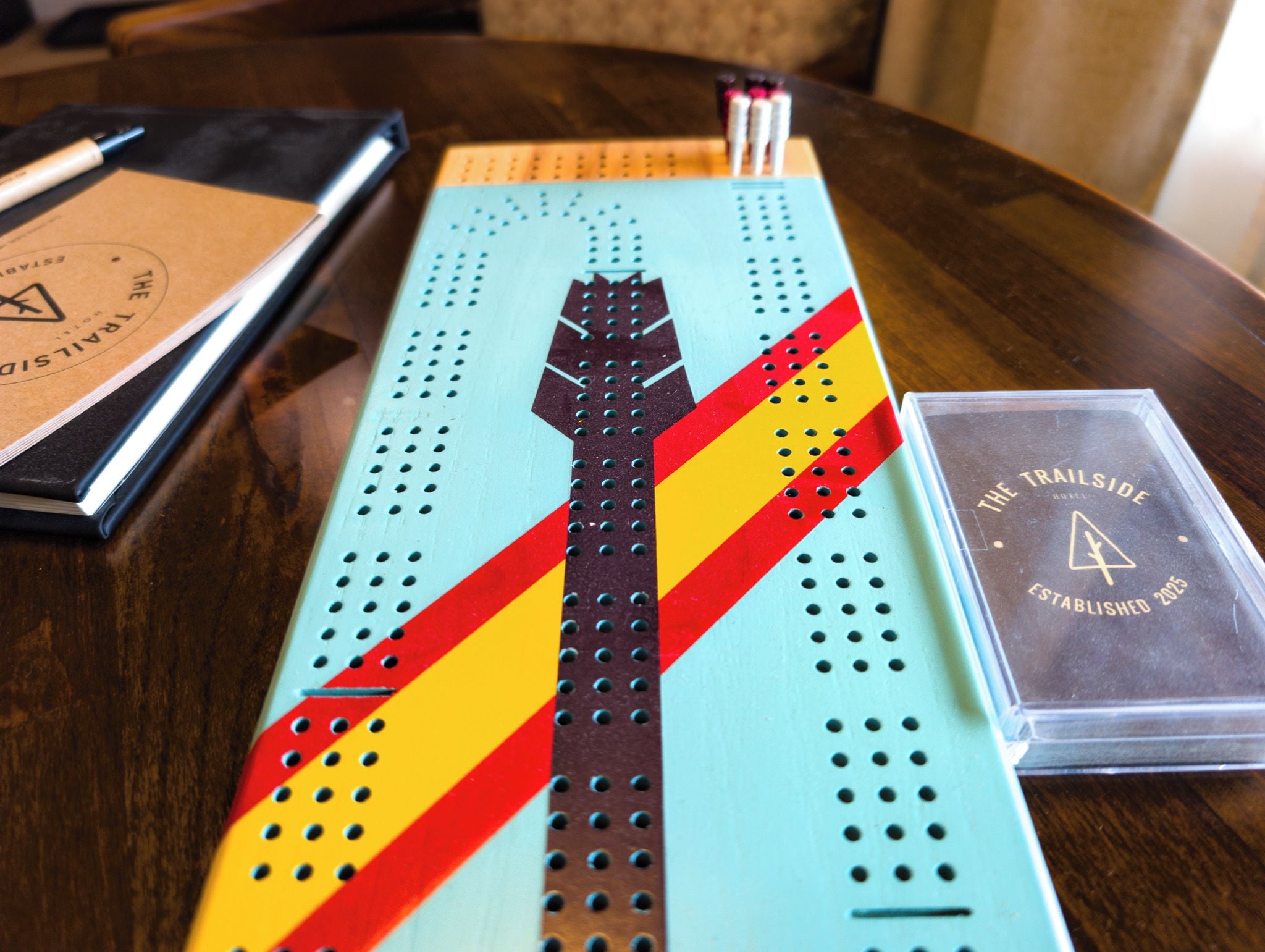 Une table sur laquelle se trouvent un objet rayé de bleu et de jaune, un stylo noir et blanc et une trousse transparente avec du texte.