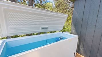An outdoor ice chest with a blue interior, placed on a wooden deck.