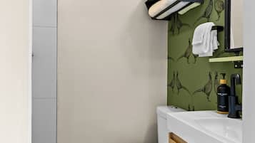 A modern bathroom with a toilet, a sink with a mirror, and a towel rack.