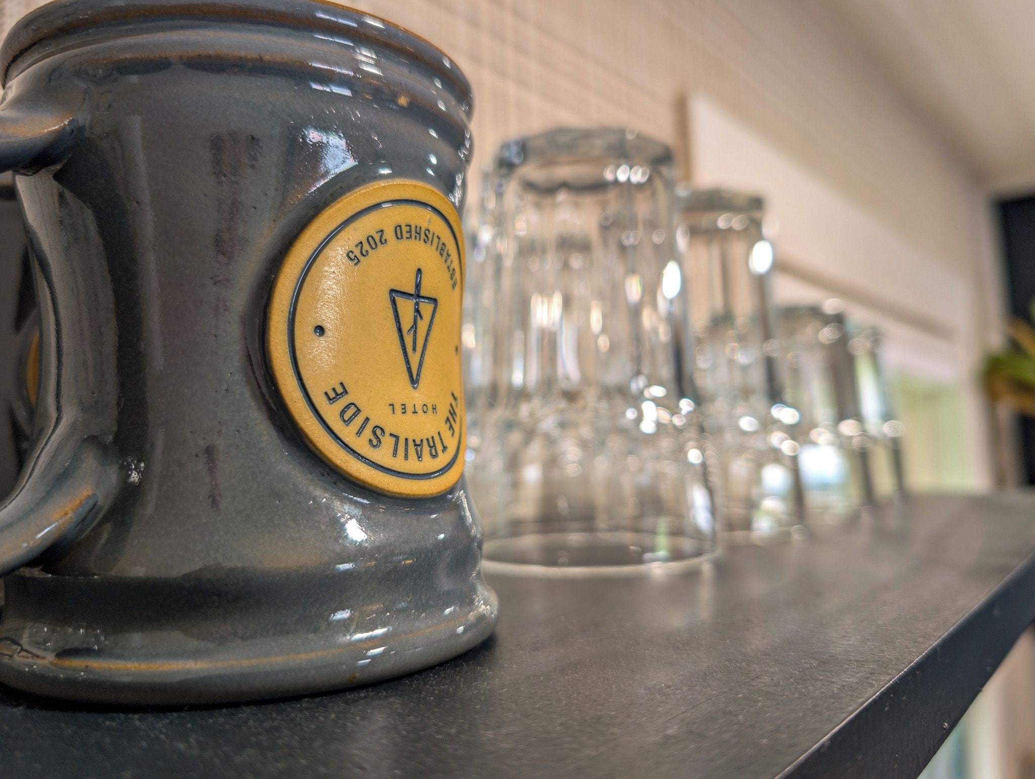 A row of clear glass mugs with a yellow label on a metal surface.