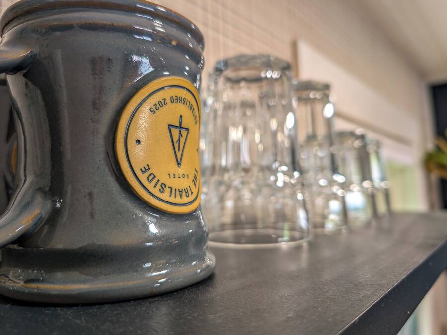 A row of clear glass mugs with a yellow label on a metal surface.