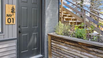 A black door with a wooden sign reading 'No 01' and a wooden staircase leading to a garden area.