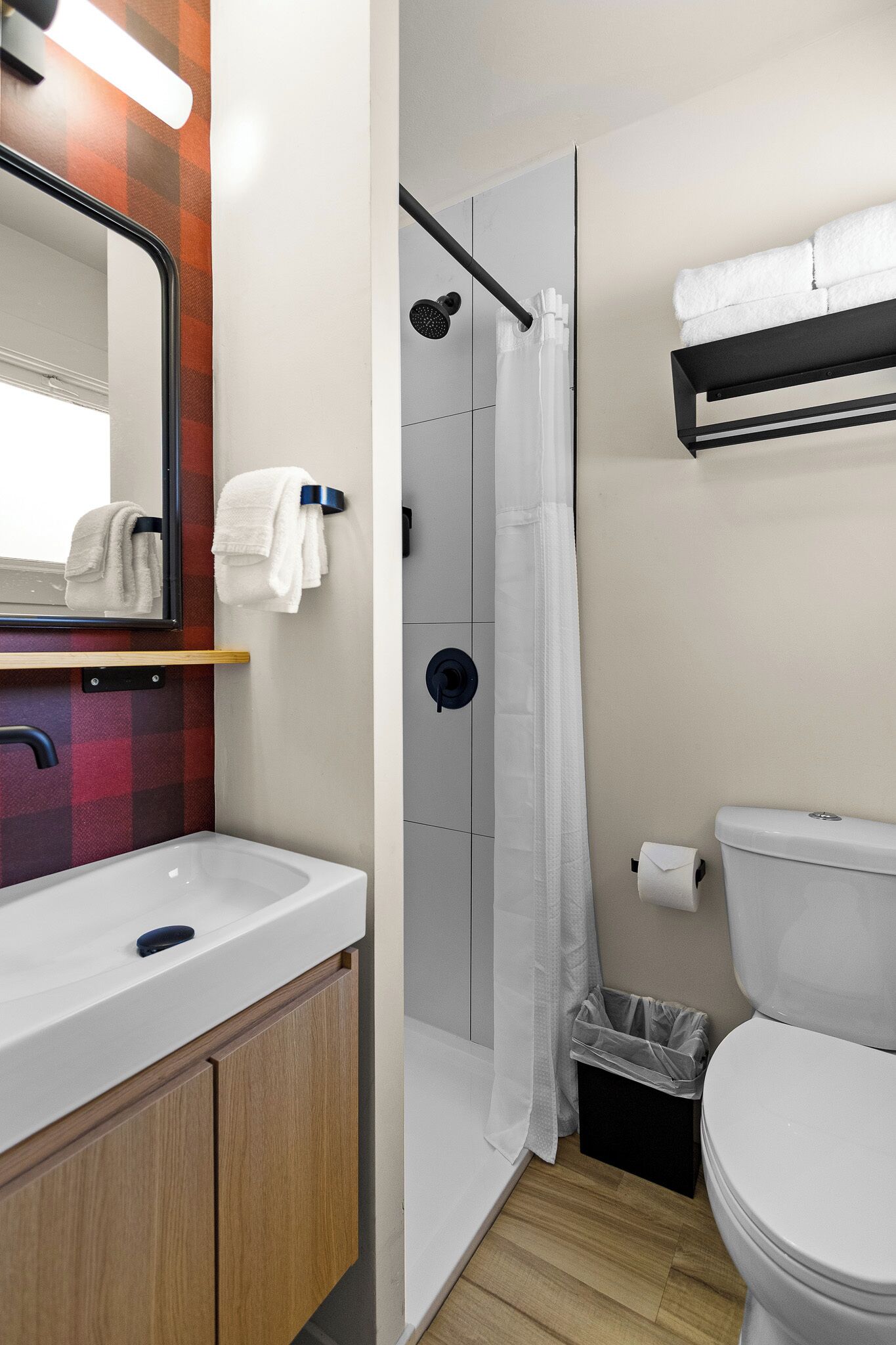 Baño con ducha, inodoro, lavabo y espejo.
