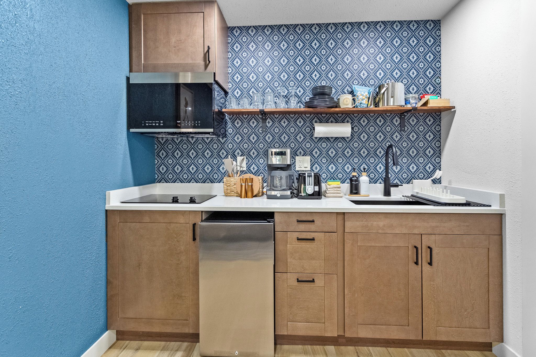 A compact kitchen with a microwave, toaster, coffee maker, and a sink.