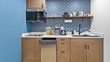 A compact kitchen with a microwave, toaster, coffee maker, and a sink.